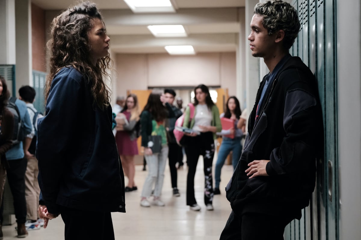 Zendaya as Rue and Dominic Fike as Elliot in 'Euphoria' Season 2. Rue and Elliot talk in the school hallway.