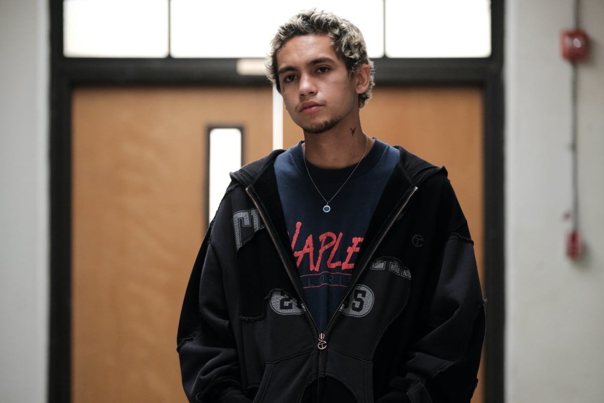Dominic Fike as Elliot in 'Euphoria' Season 2. Elliot wears a T-shirt and jacket. He has dyed hair and a face tattoo.