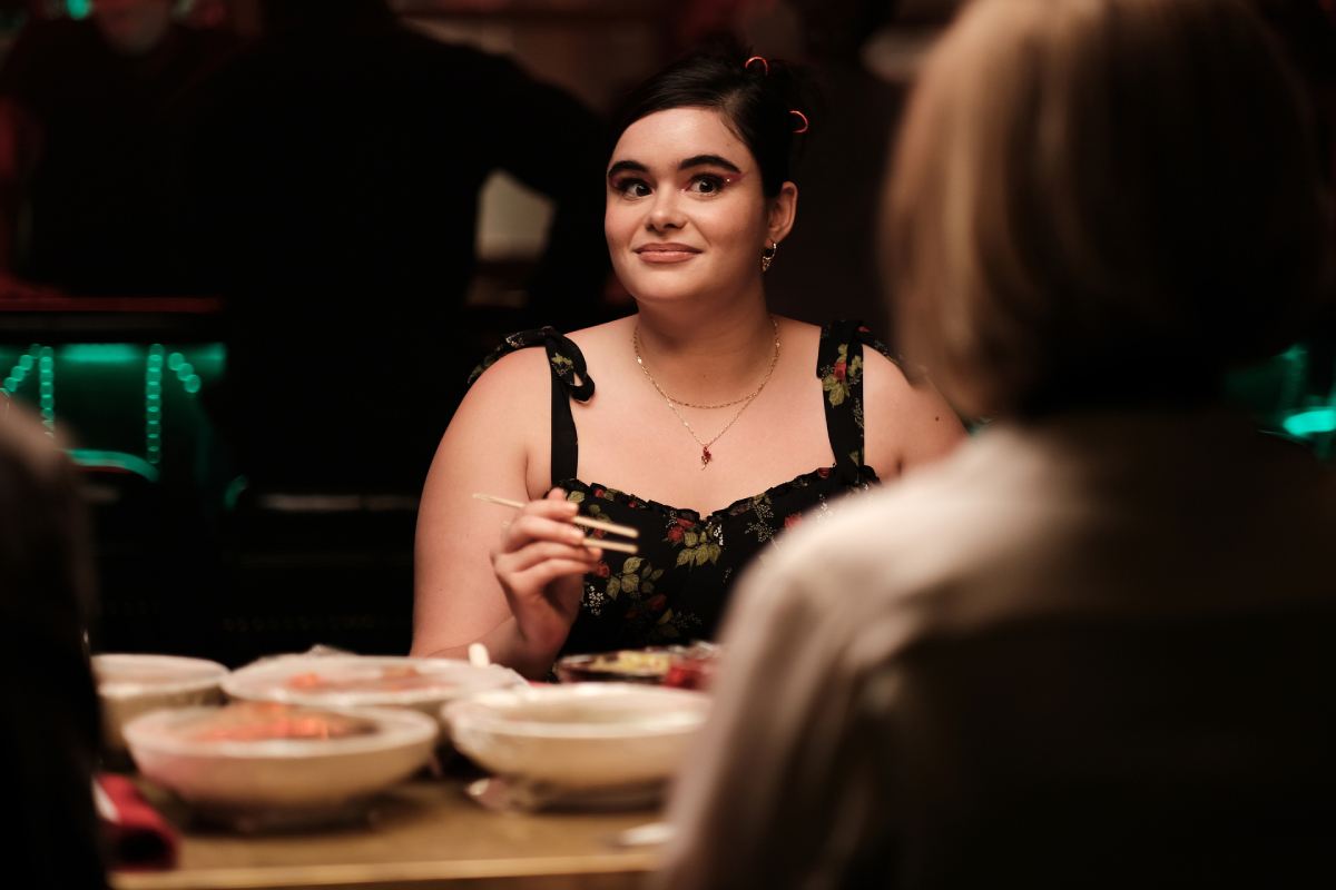 Barbie Ferreira as Kat in Euphoria Season 2. Kat sits across the table holding a pair of chopsticks and looking uncomfortable.