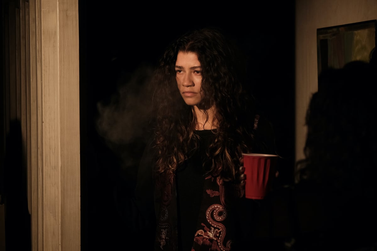 Zendaya as Rue Bennett in Euphoria Season 2 wearing a costume that consists of a black shirt with a red pattern on the side.
