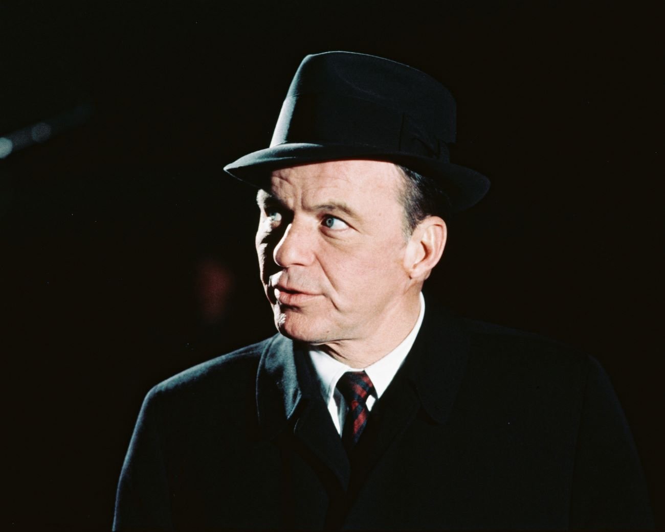 Frank Sinatra wears a hat and a red tie.