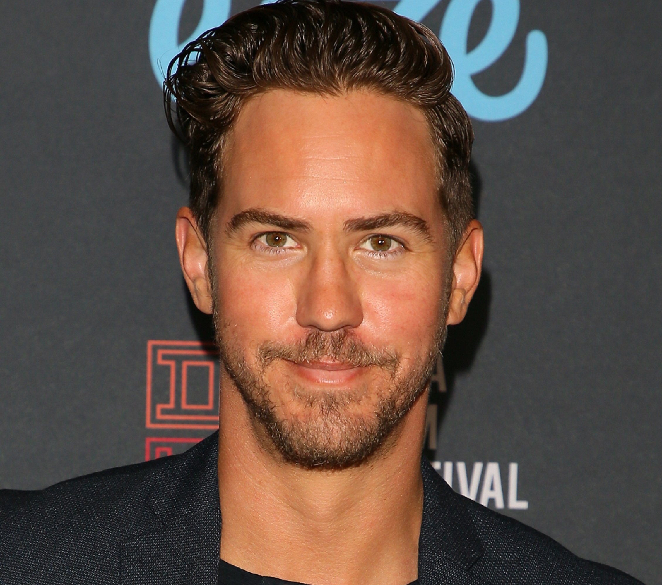 'General Hospital' star Wes Ramsey, who plays Peter August, smiling and wearing a black suit.