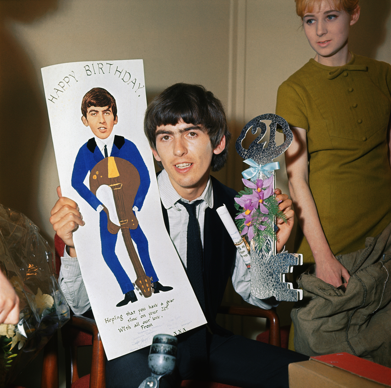 George Harrison holding up some of the birthday cards he received from fans for his 21st birthday in 1964.