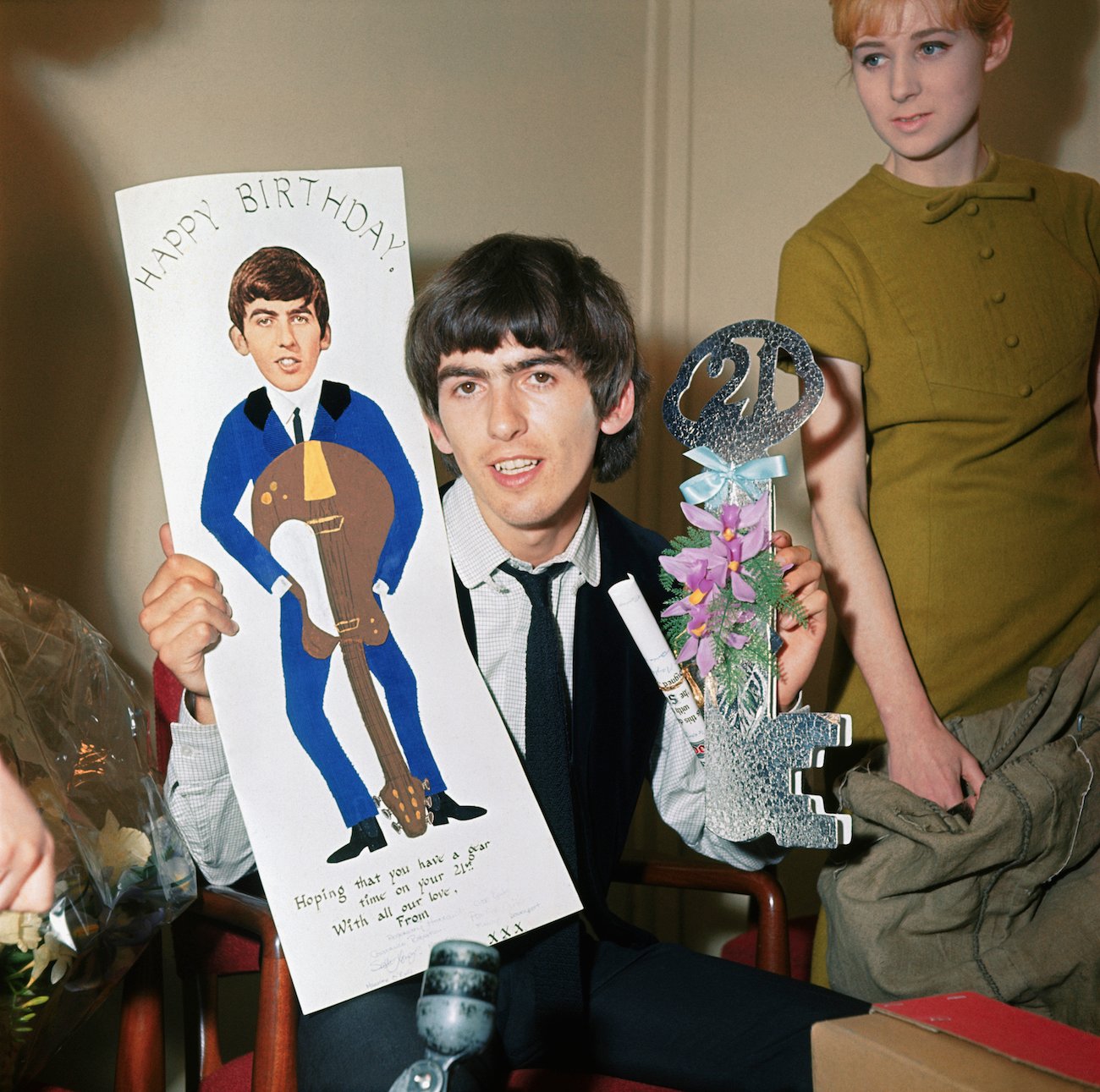 George Harrison holding up some of the birthday cards he received from fans for his 21st birthday in 1964.