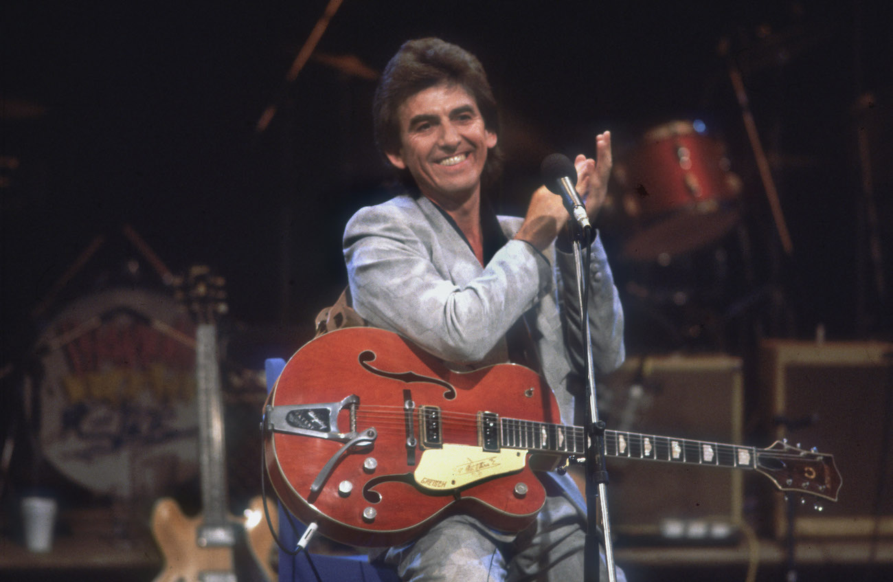 George Harrison wearing a suit while performing during Ferry Aid in 1987.