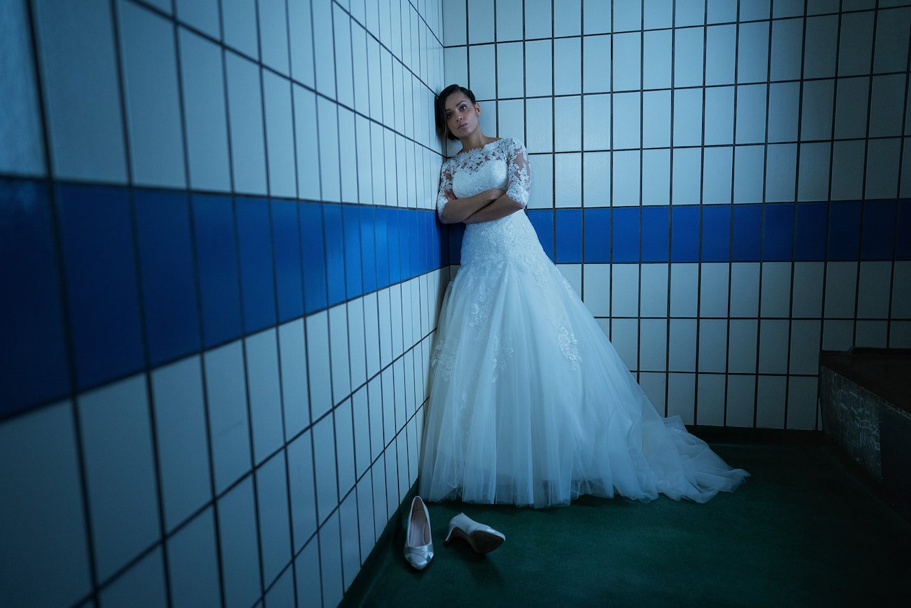 Georgina Campbell leans against a wall in a white wedding gown