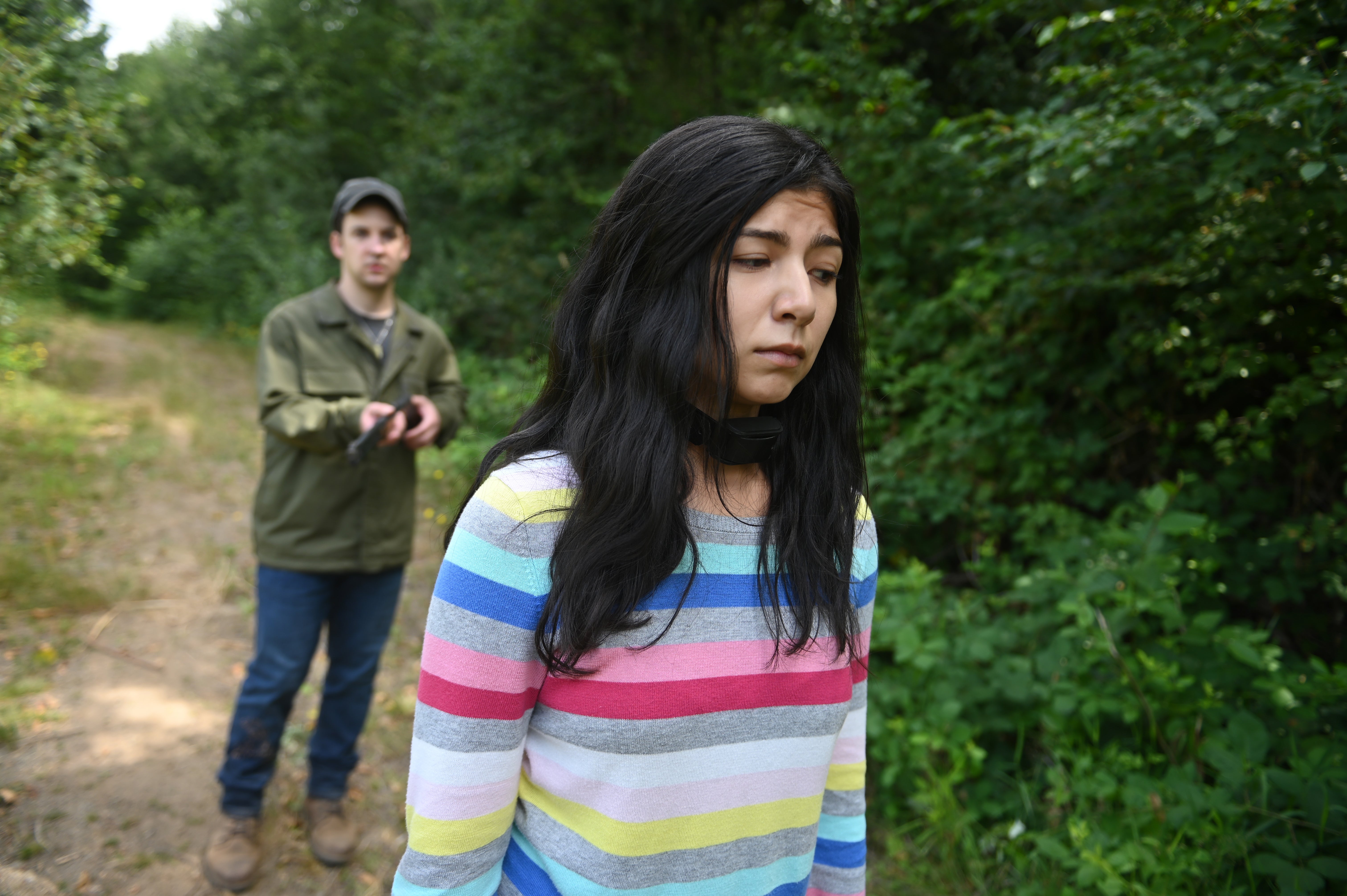 Lindsay Navarro, wearing a striped shirt, with Ben Savage in the background in 'Girl in the Shed'