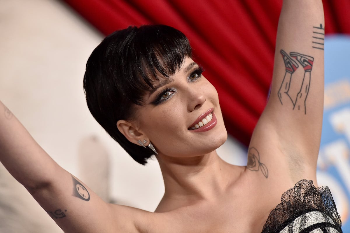Halsey smiles with her arms up at an event.