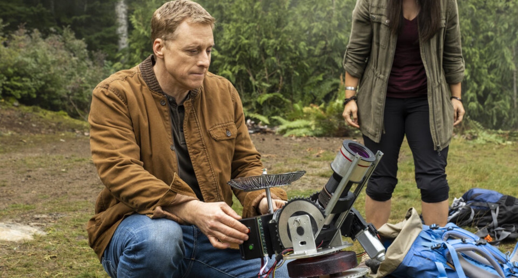 Harry and radio in 'Resident Alien' Season 2 in the woods in relation to alien phone number.