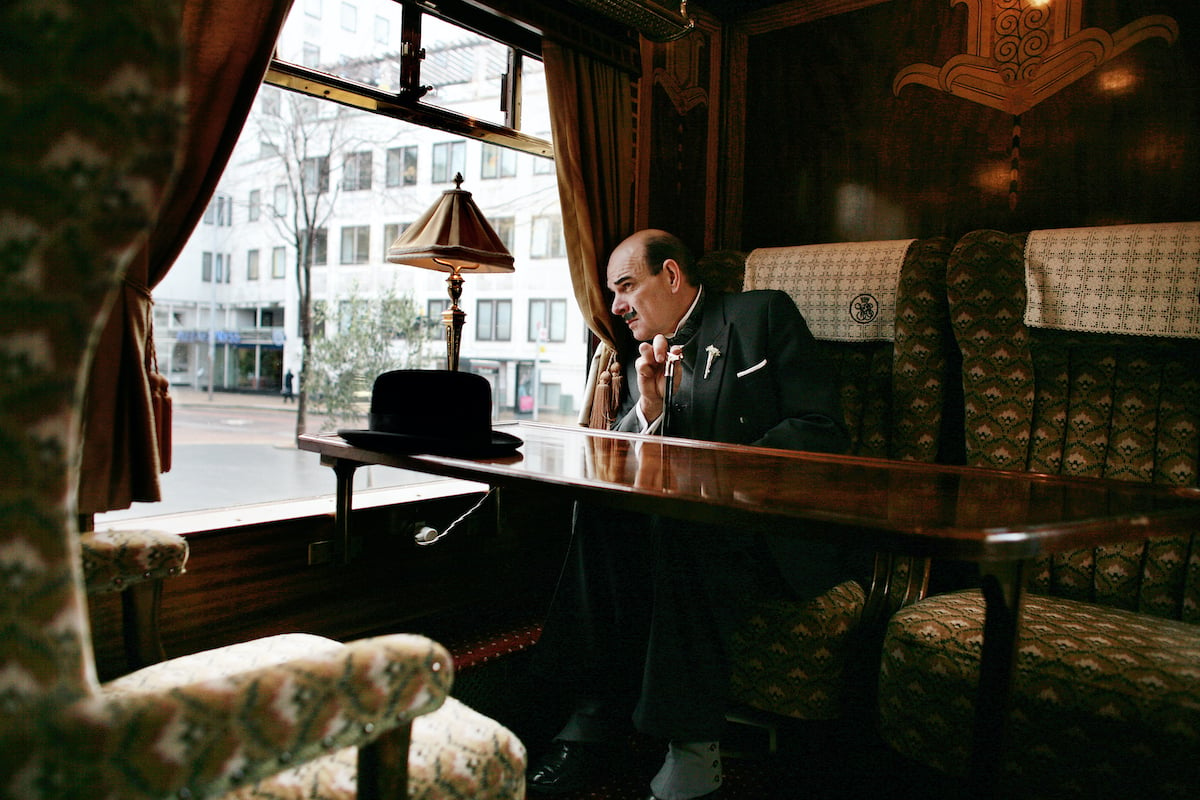 An actor dressed as Hercule Poirot sitting in an original first class parlour car, "Zena" from the Orient Express train, built in 1928 and decorated in the Art Deco style, with wooden panelling and table with bowler hat
