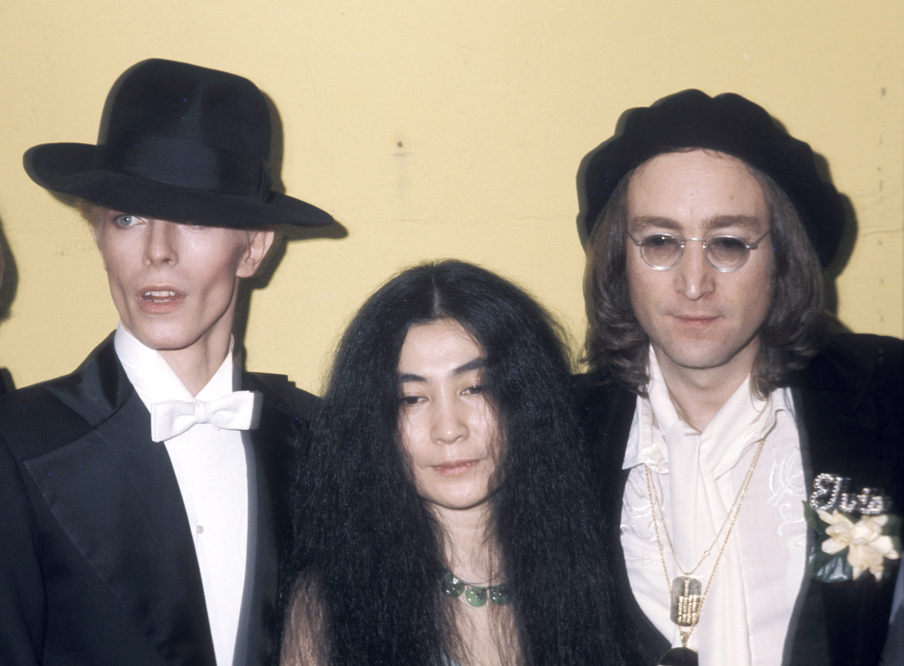 David Bowie, Yoko Ono, and John Lennon in front of a wall