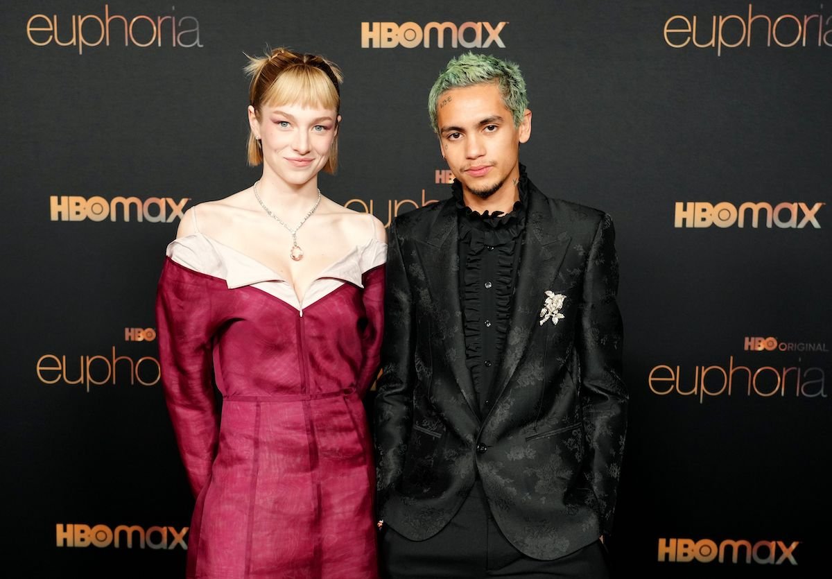 (L-R) Hunter Schafer and Dominic Fike smiling in front of a black background