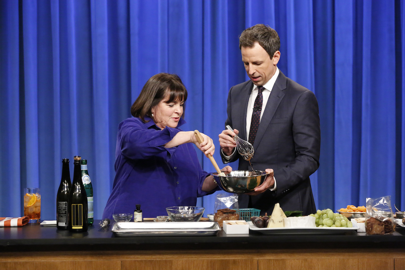 Ina Garten and Seth Meyers smile as they stir the contents of a bowl