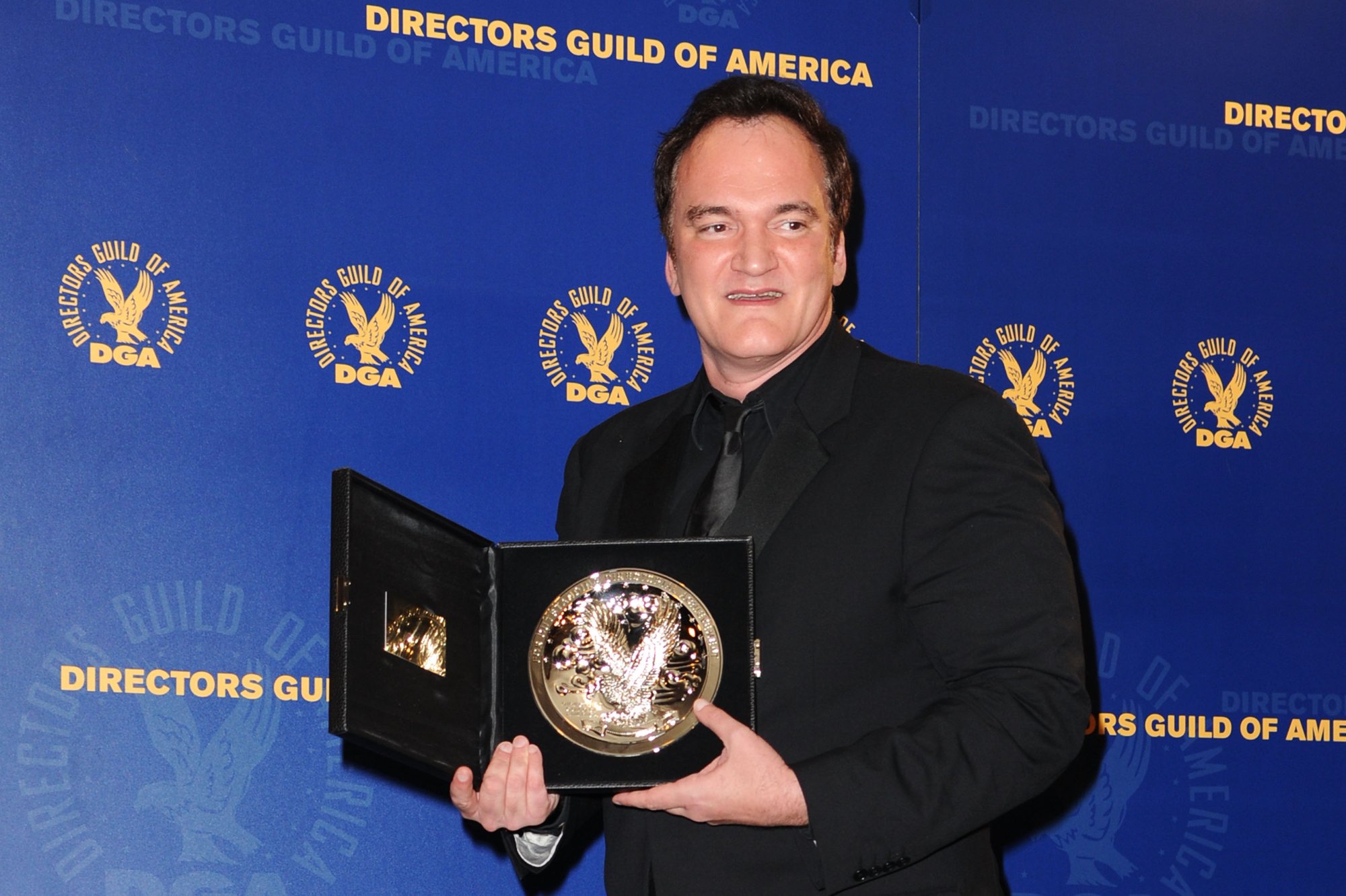'Inglourious Basterds' filmmaker Quentin Tarantino holding a plaque wearing a black suit