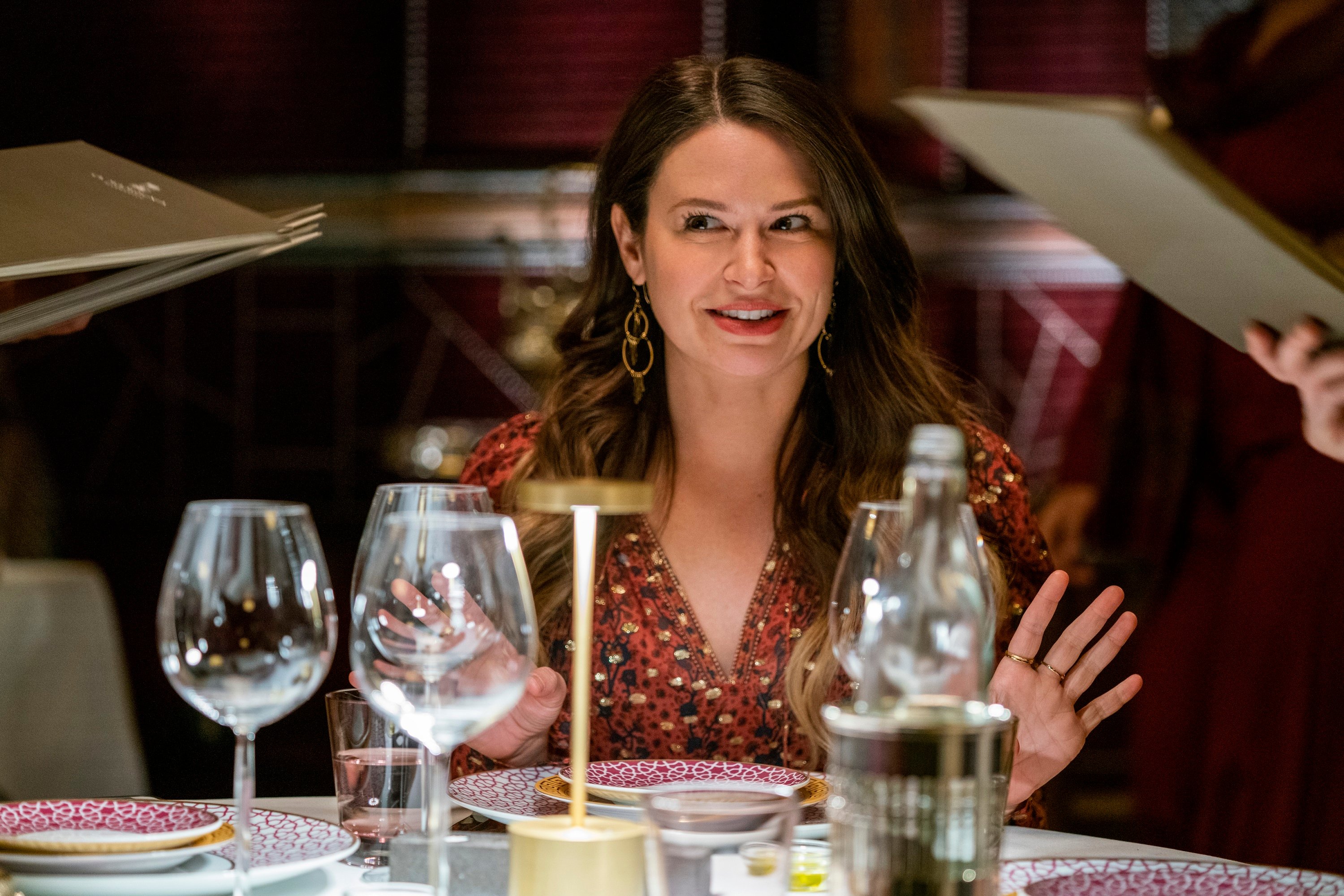'Inventing Anna' cast member Katie Lowes portrays Rachel Williams with her hands up in front of several glasses