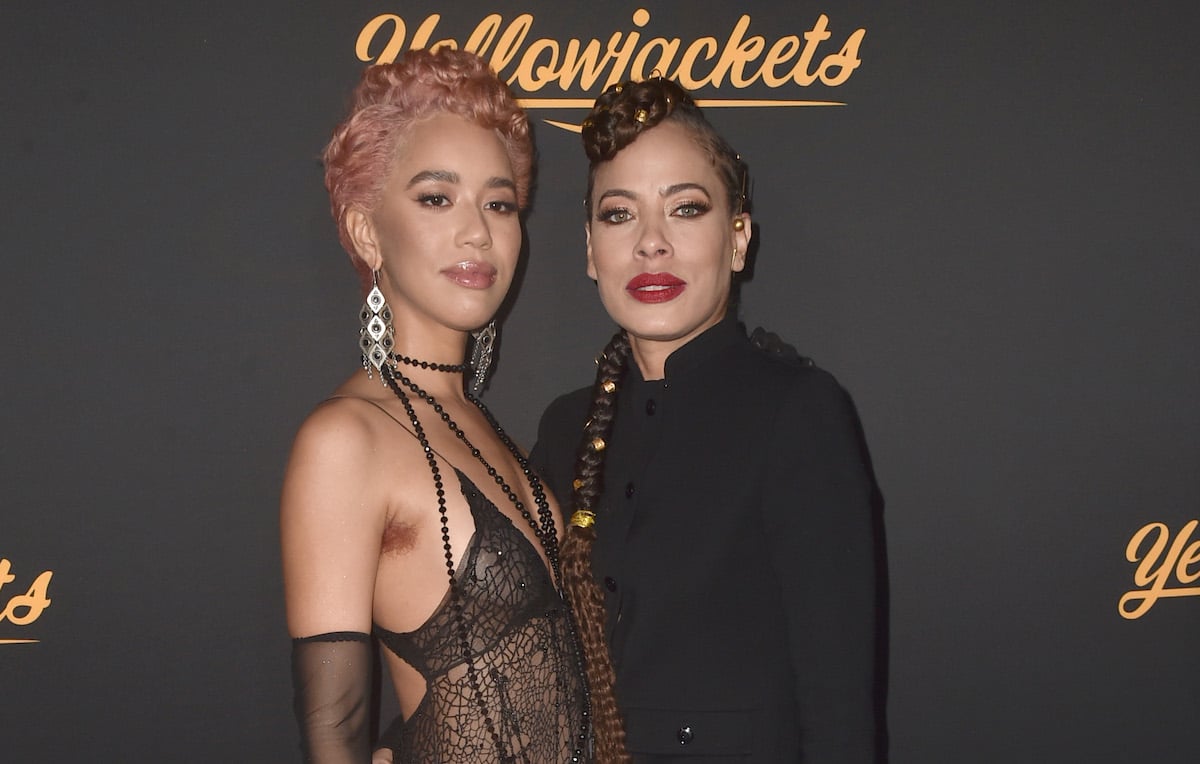Jasmin Savoy Brown poses in a black lace dress with and Tawny Cypress who wears a black suit at the Premiere Of Showtime's 'Yellowjackets'.