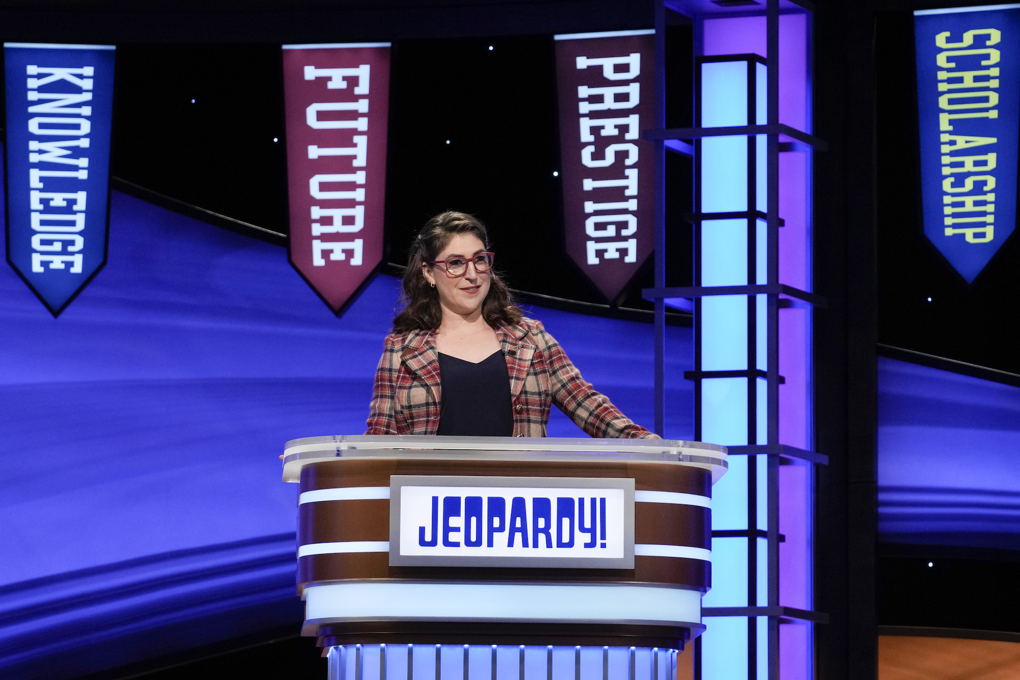 'Jeopardy!' host Mayim Bilaik stands at the podium reading questions
