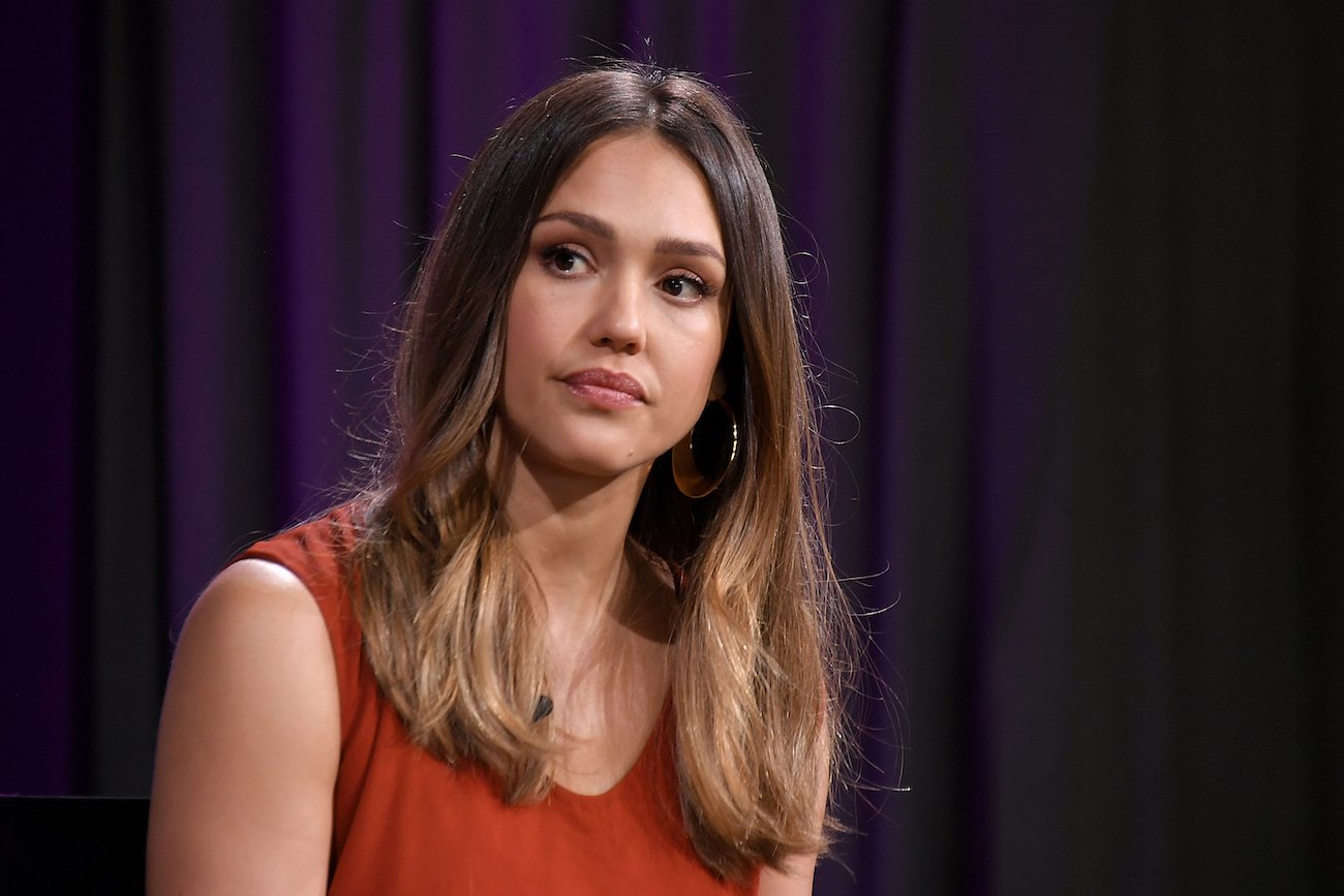 Jessica Alba looking on in front of a dark background