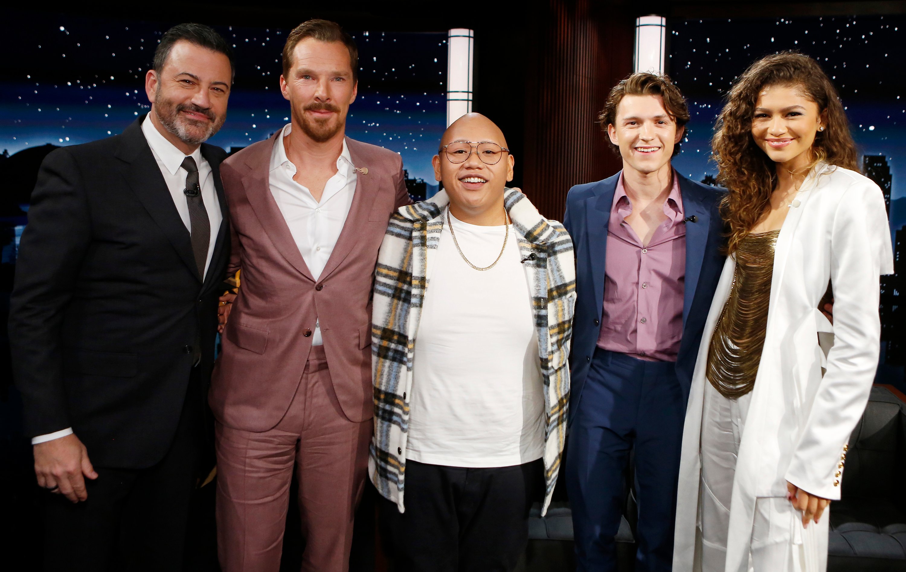 Jimmy Kimmel, who wanted the Marvel film 'Spider-Man: No Way Home' to be nominated at the 2022 Oscars, Benedict Cumberbatch, Jacob Batalon, Tom Holland, and Zendaya post together for a picture while on 'Jimmy Kimmel Live.' Kimmel wears a black suit. Cumberbatch wears a purple/pink suit. Batalon wears a yellow, black, and white plaid jacket over a white shirt. Holland wears a blue suit over a purple button-up shirt. Zendaya wears a white jacket over a gold shirt.