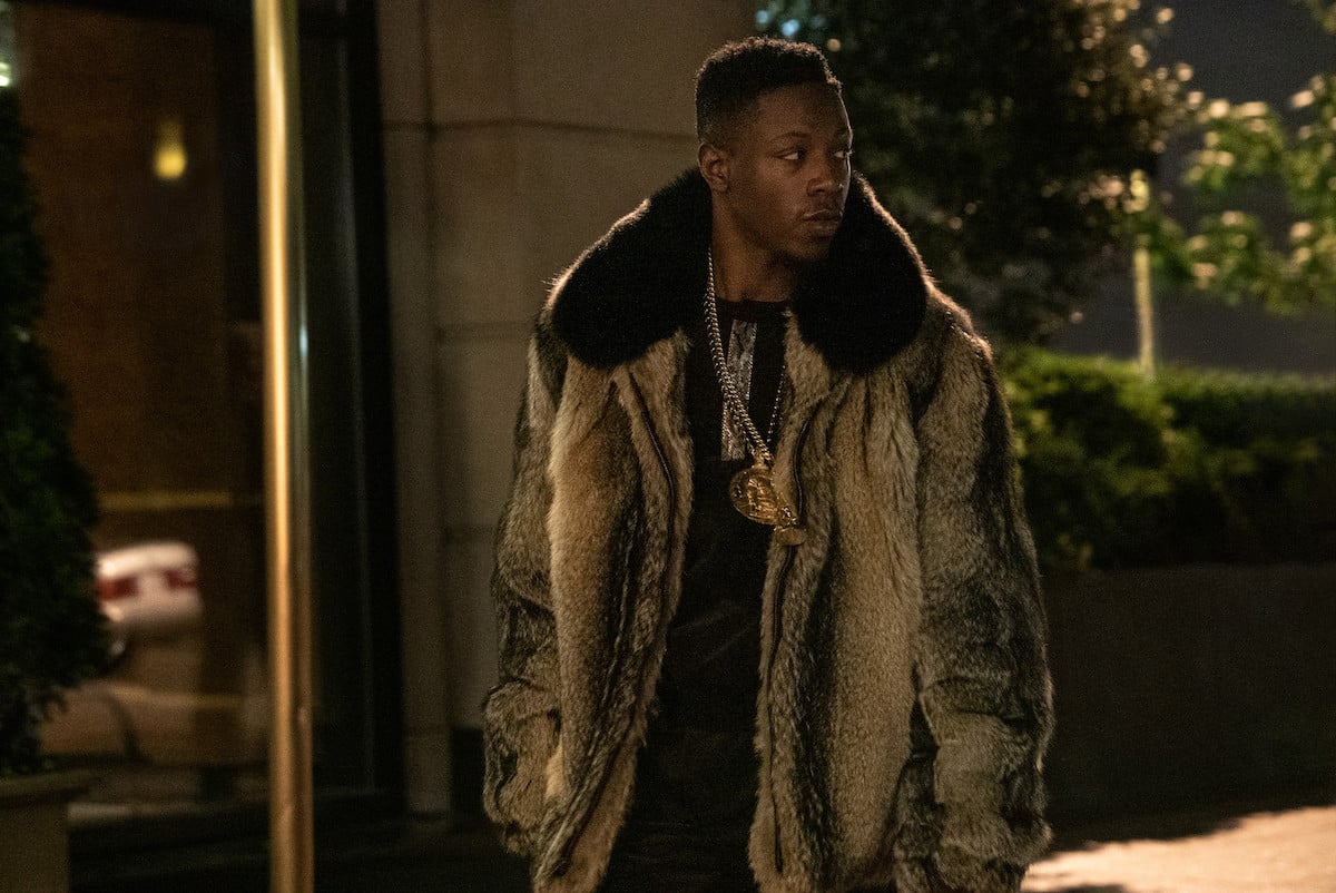 Joey Bada$$ as Unique wearing a fur coat and gold chains in 'Power Book III: Raising Kanan' 