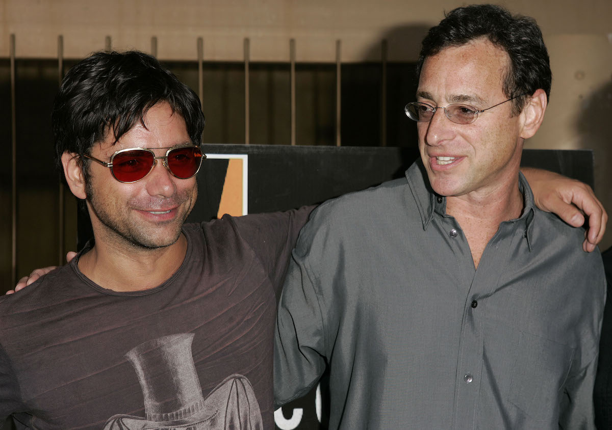 John Stamos and Bob Saget pose with their arms around each other at an event.