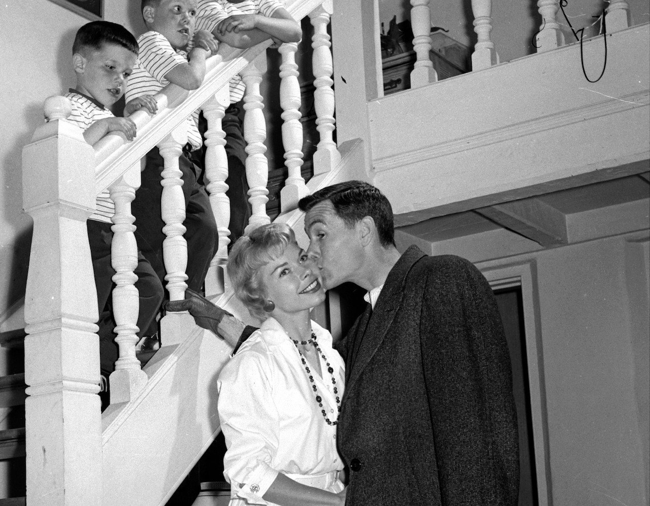 Johnny Carson kissing his wife before leaving for the studio as his sons look on at his home