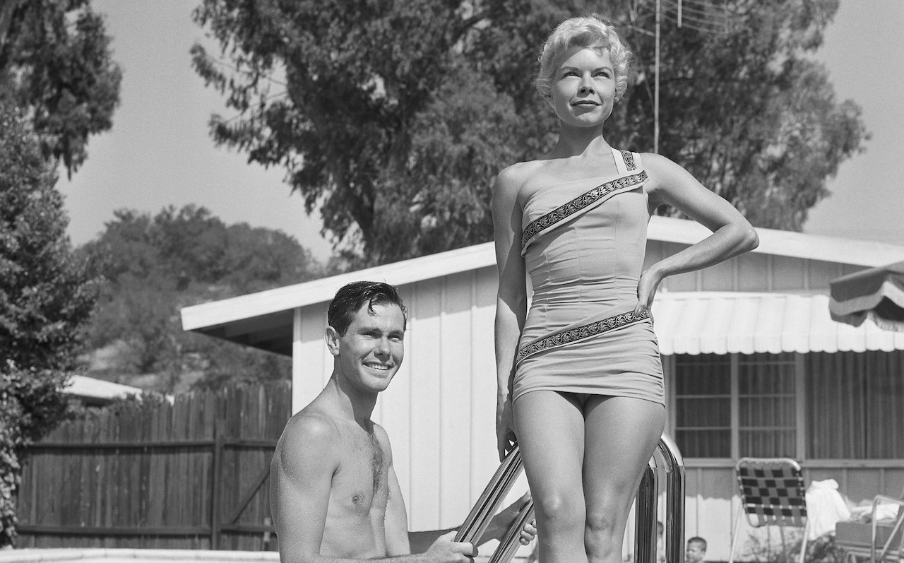 Johnny Carson and his first wife, Jody Wolcott, pose for a picture by their home swimming pool (c. 1958).