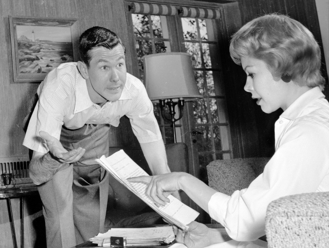 Black and white photo of Johnny Carson and his first wife, Jody Wolcott, at home and discussing a script (c. 1958)