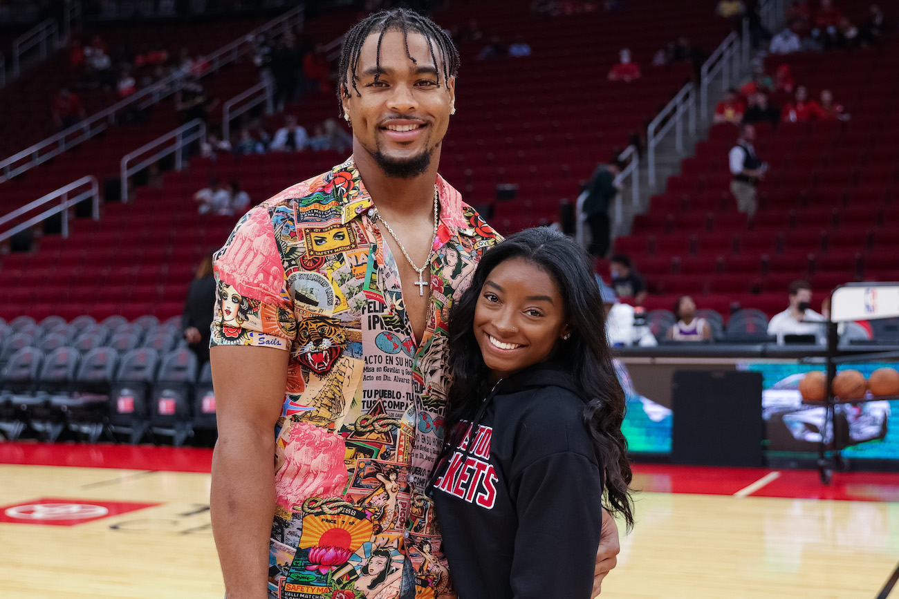 Jonathan Owens and Simone Biles posing together in an arena