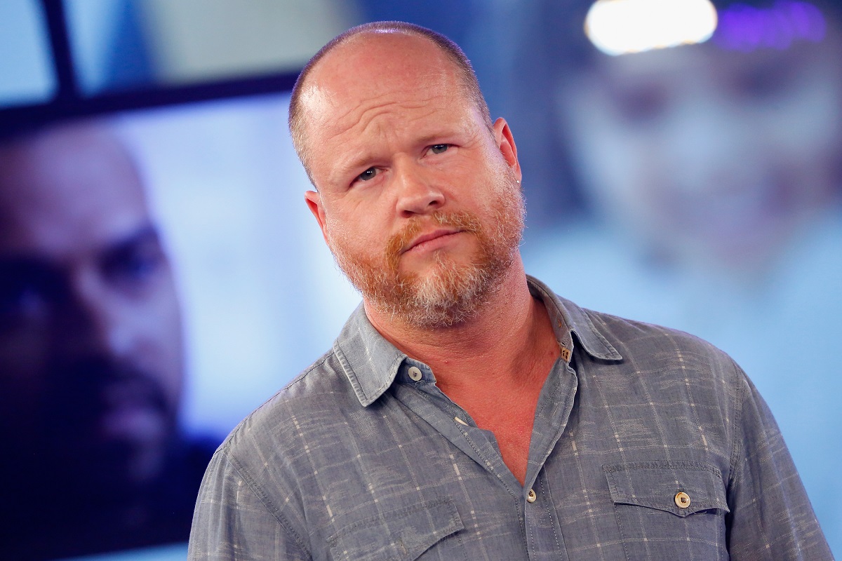 Joss Whedon posing while wearing a blue shirt.
