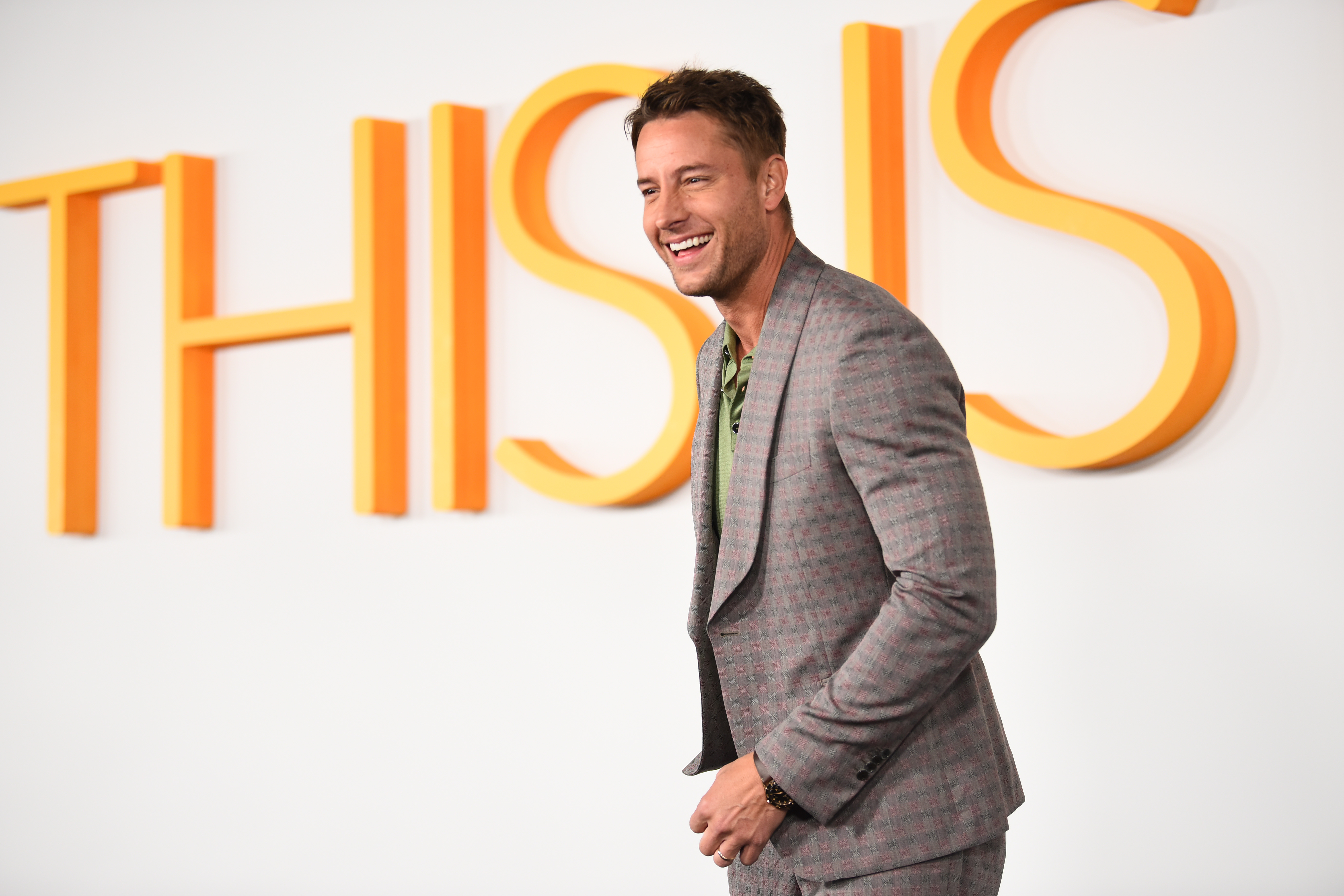 Justin Hartley, who plays Kevin in 'This Is Us,' wears a gray suit over a green shirt and matching gray pants.