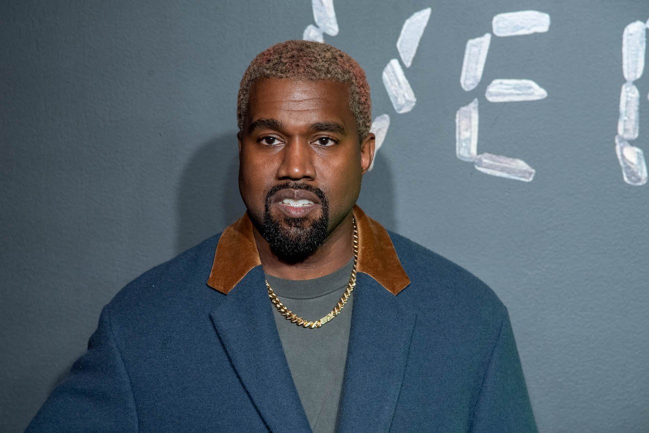 Kanye West looking on in front of a gray background