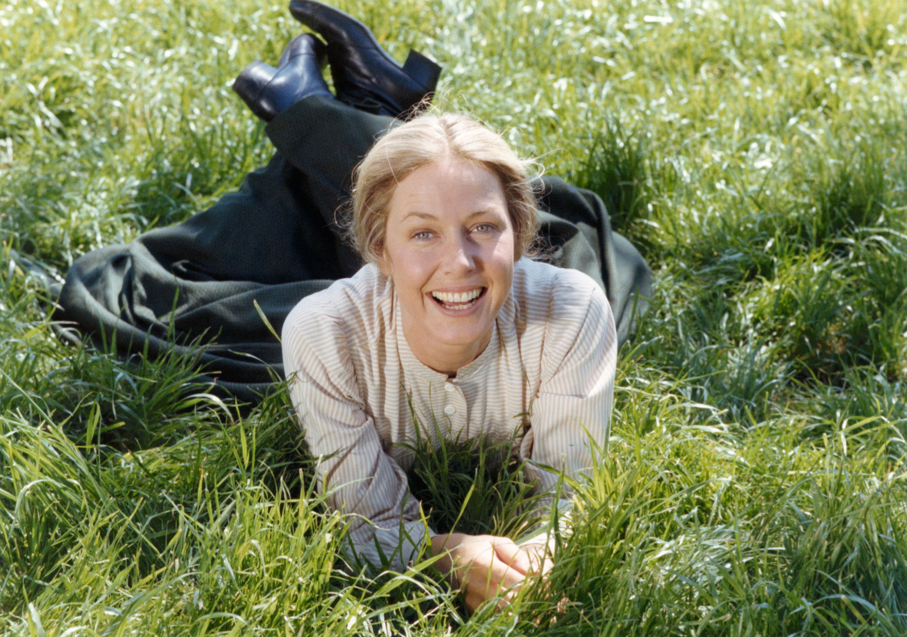 Karen Grassle lies in the grass as she portrays Caroline Ingalls on Little House on the Prairie.