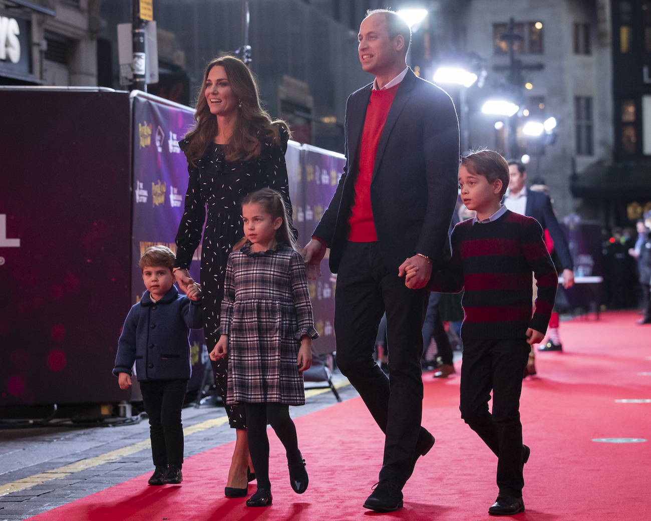 Kate Middleton and Prince William walking with Prince Louis, Prince George, and Princess Charlotte on a red carpet