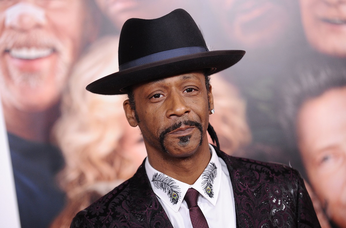 Katt Williams smirking while wearing a suit.