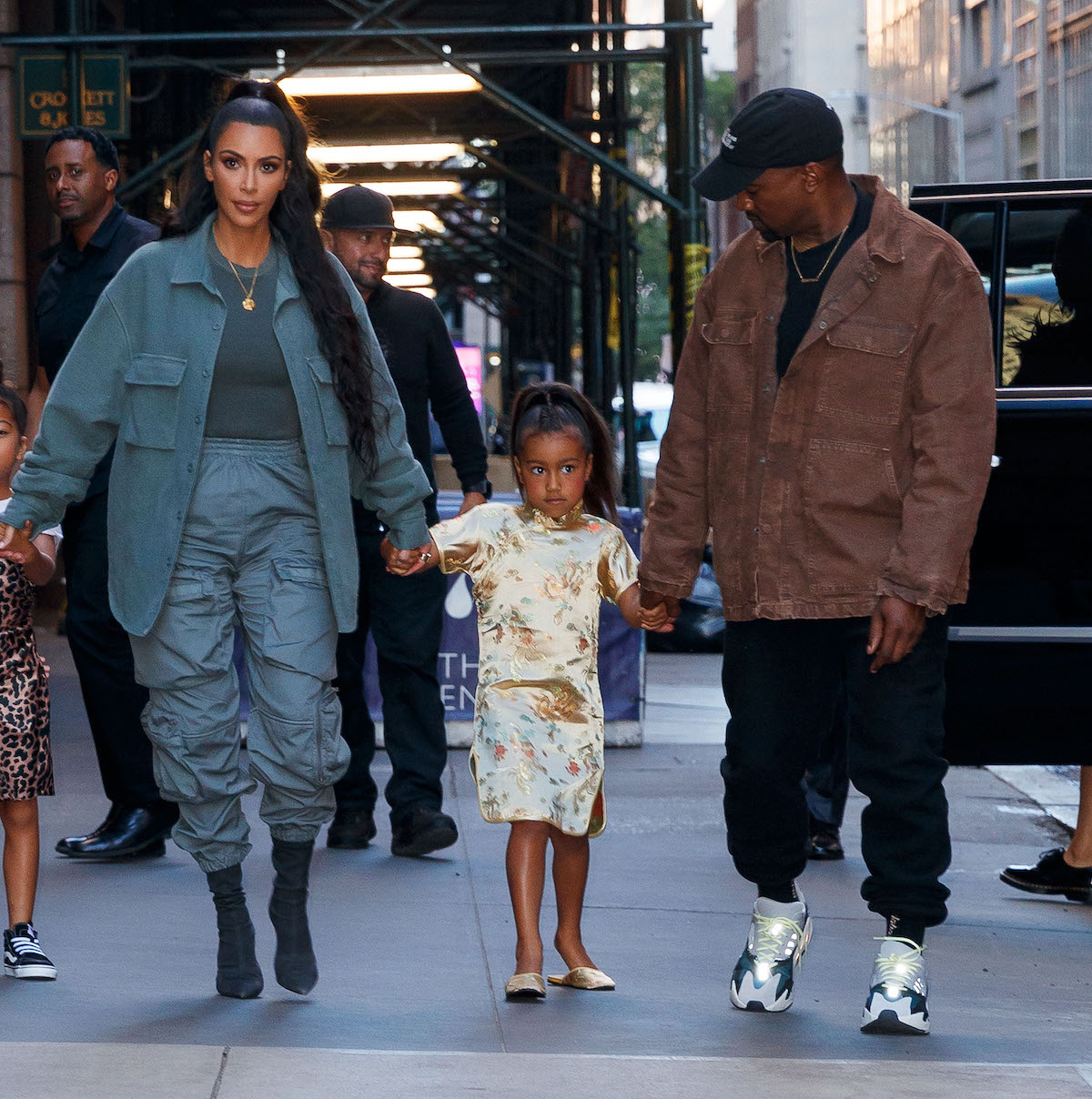Kim Kardashian West, North West, and Kanye West walk together.