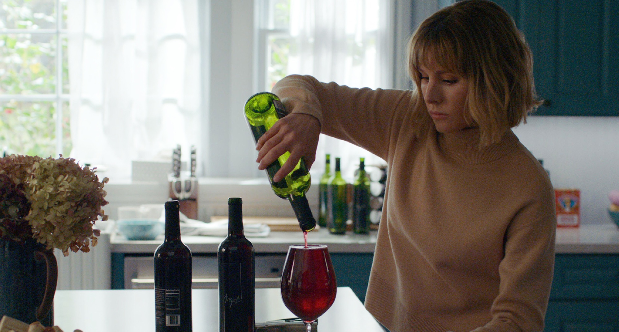 Kristen Bell and wine in 'The Woman in the House Across the Street From the Girl in the Window' pouring a glass in kitchen.