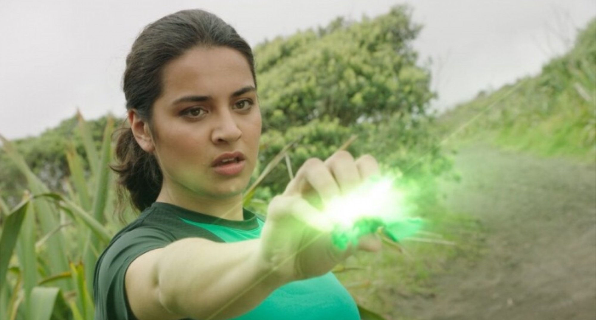 LGBTQ character Izzy in 'Power Rangers Dino Fury' holding green power crystal.