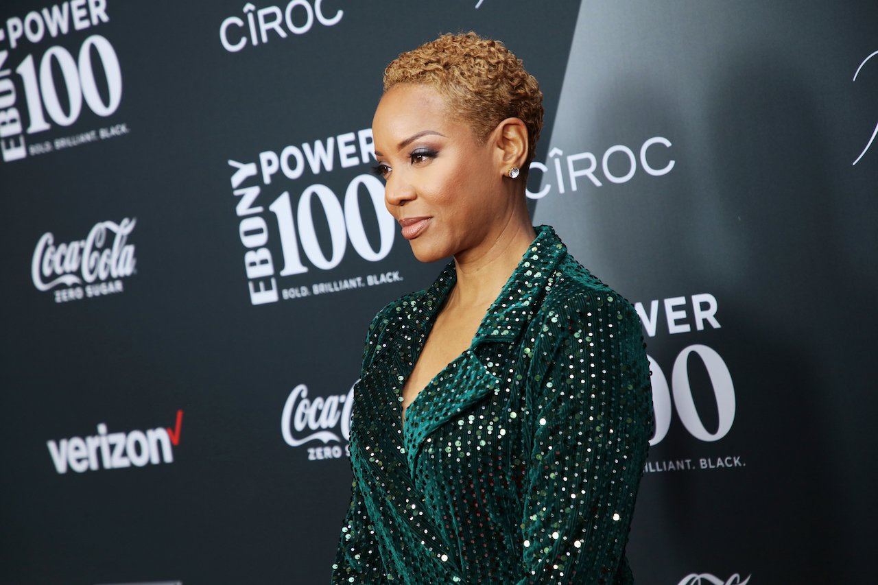 MC Lyte poses on the red carpet in a green and silver outfit.