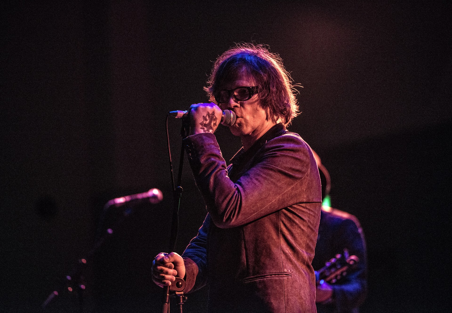Mark Lanegan performs in a dark suit at a concert.
