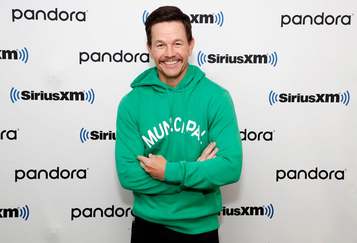 Mark Wahlberg smiling while wearing a green sweater and a mustache.