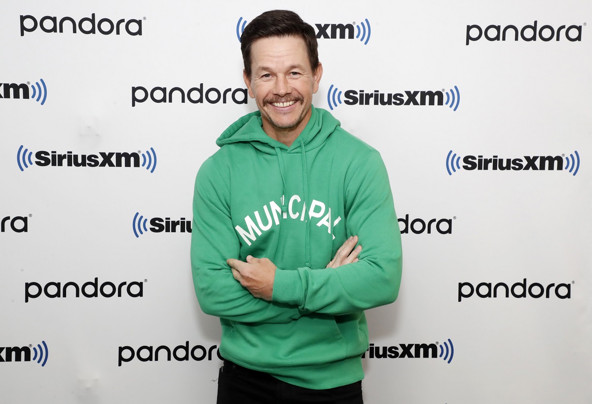 Mark Wahlberg smiling while wearing a green sweater and a mustache.