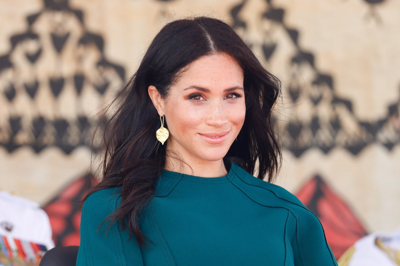 Meghan Markle wearing a teal outfit and looking into the camera