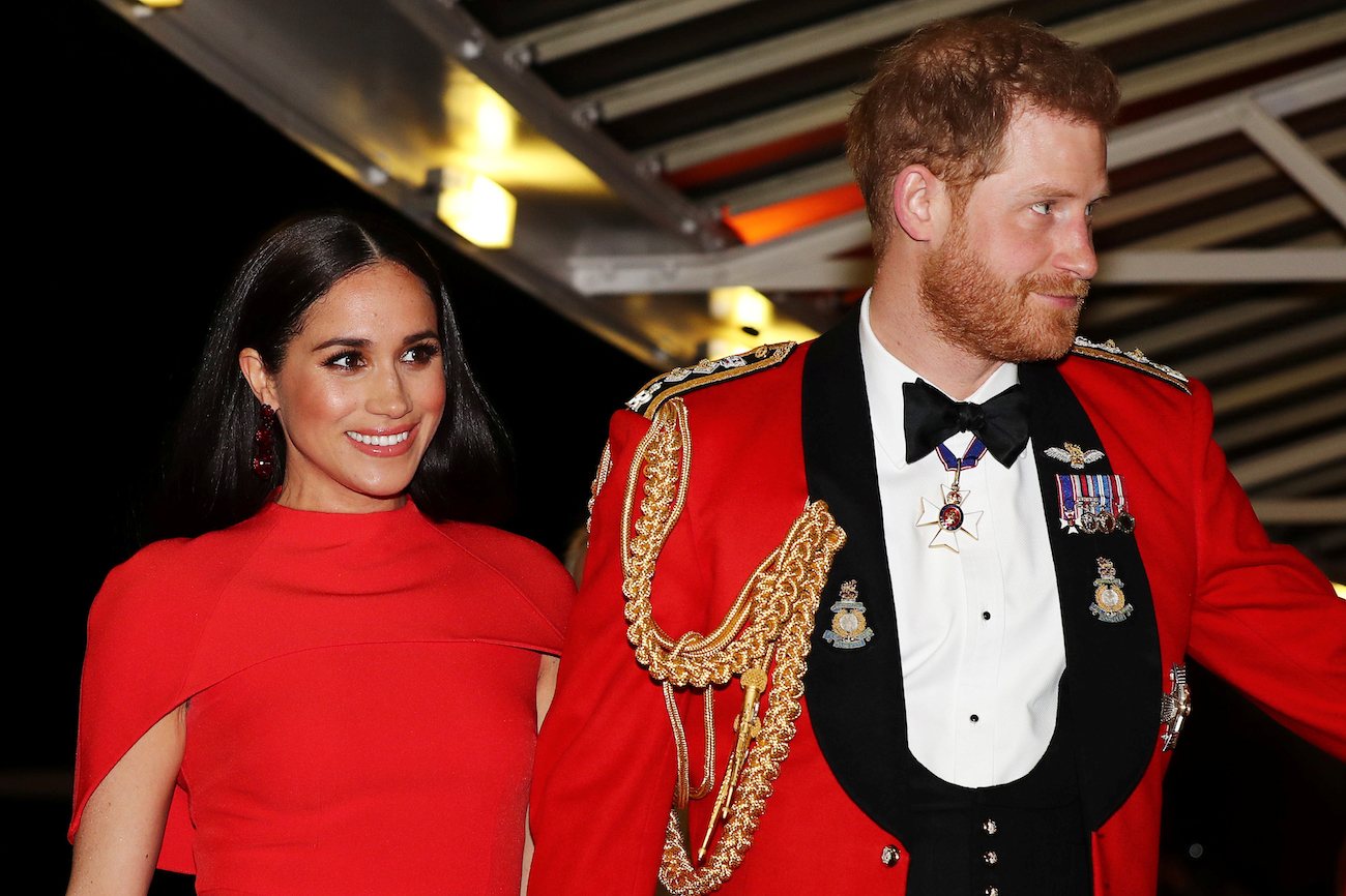 Meghan Markle wearing red outfit, Prince Harry wearing a military uniform