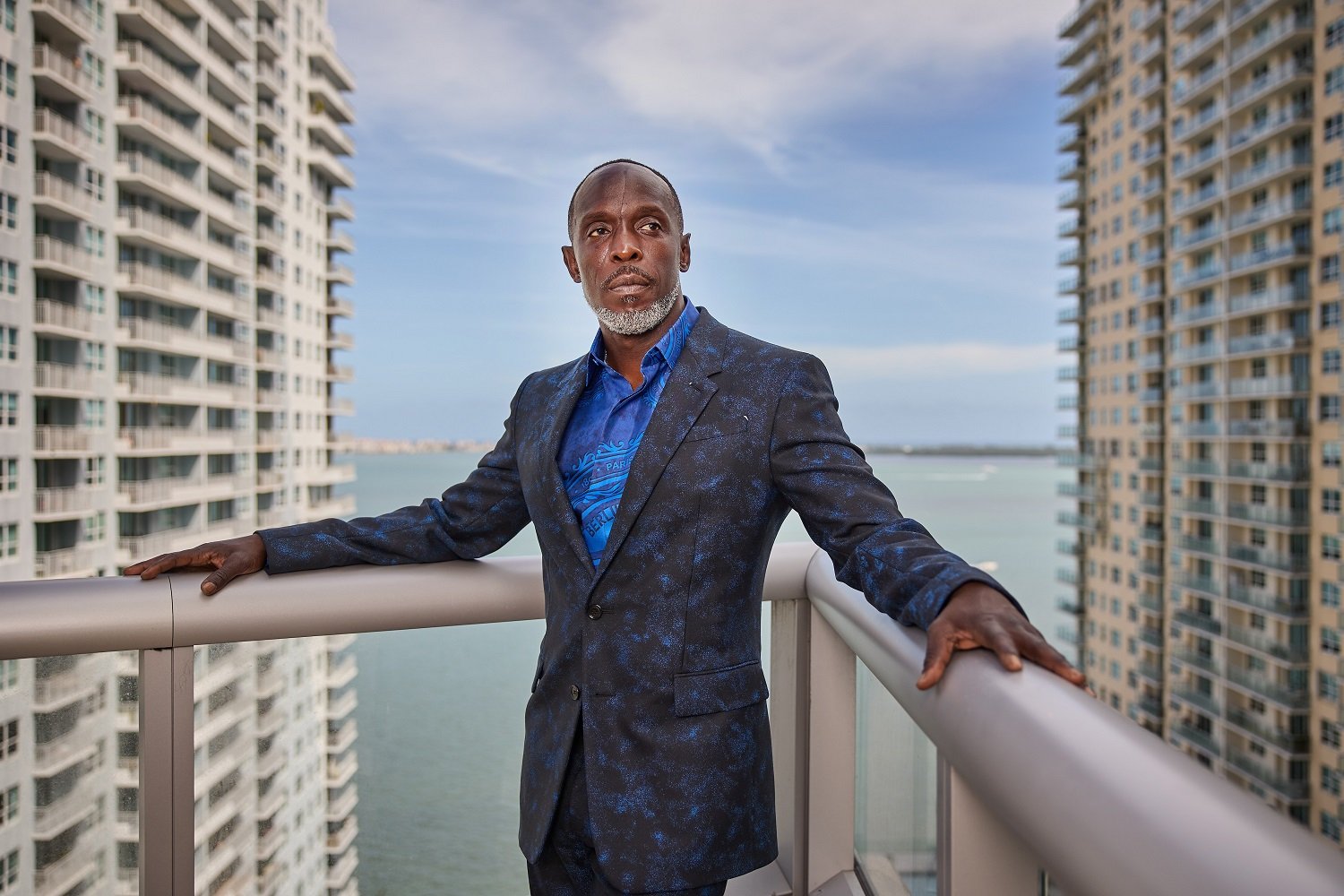 Michael K Williams in a grey suit overlooking New York City