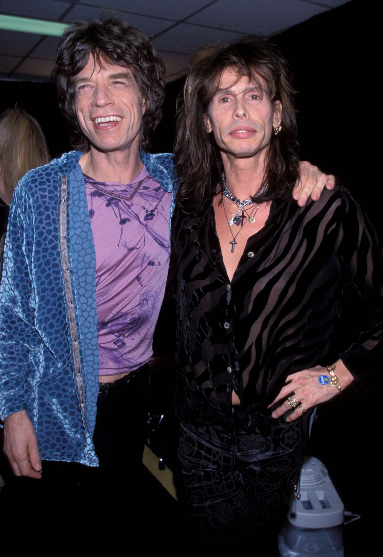 Mick Jagger wearing purple and blue embracing Steven Tyler wearing black in 1997.
