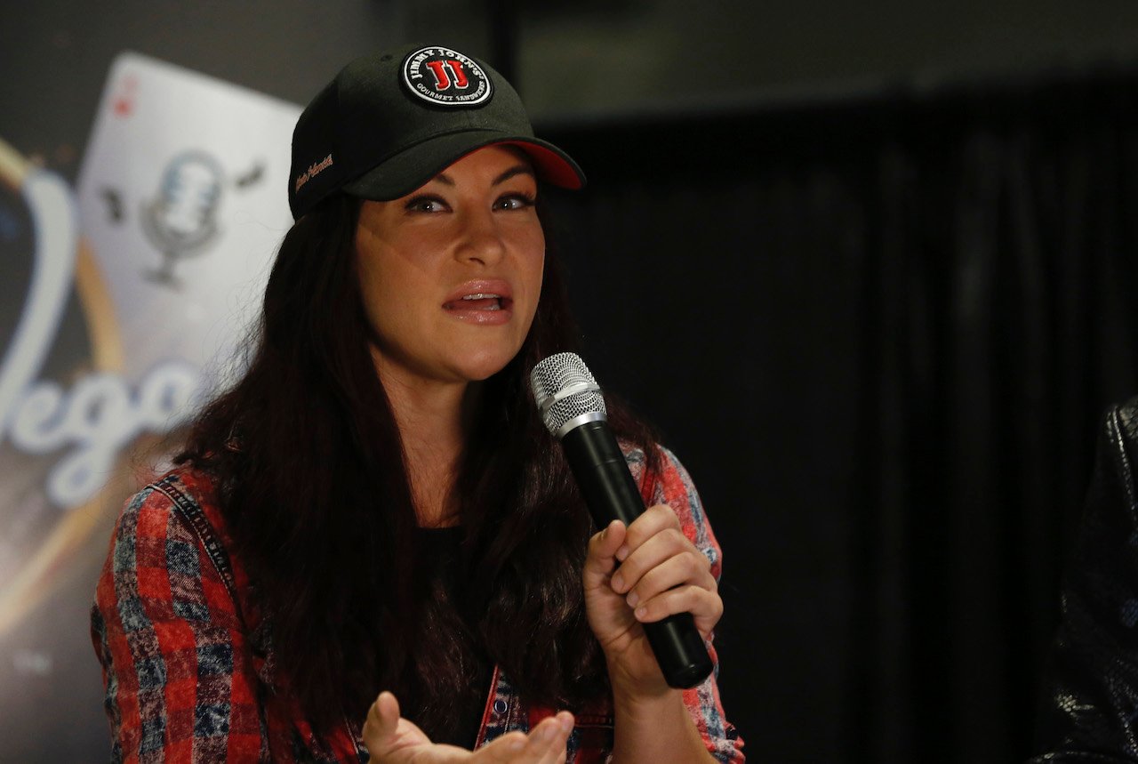 Miesha Tate talks as she holds a microphone while sitting down.