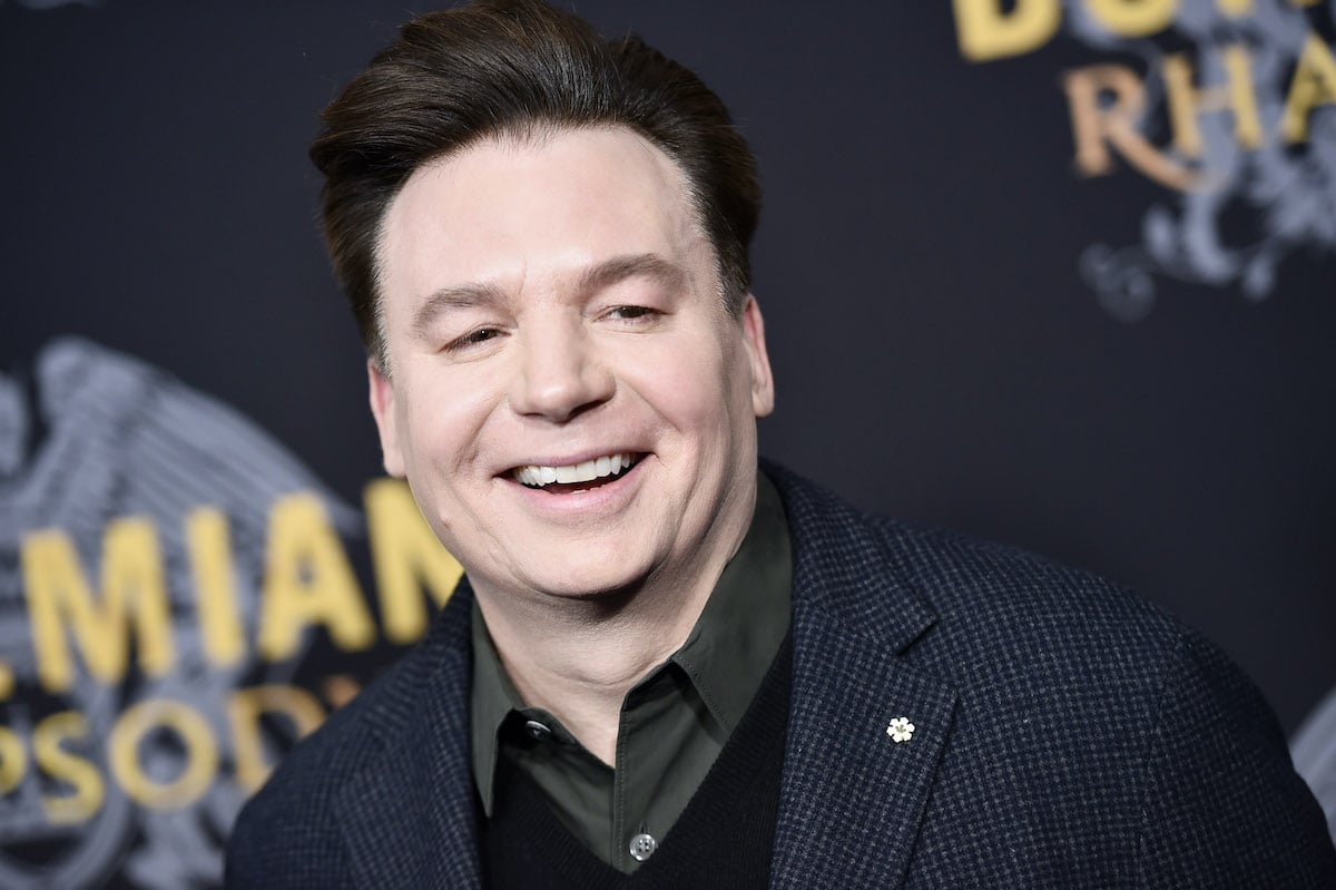 Mike Myers wears a dark suit and smiles on the red carpet