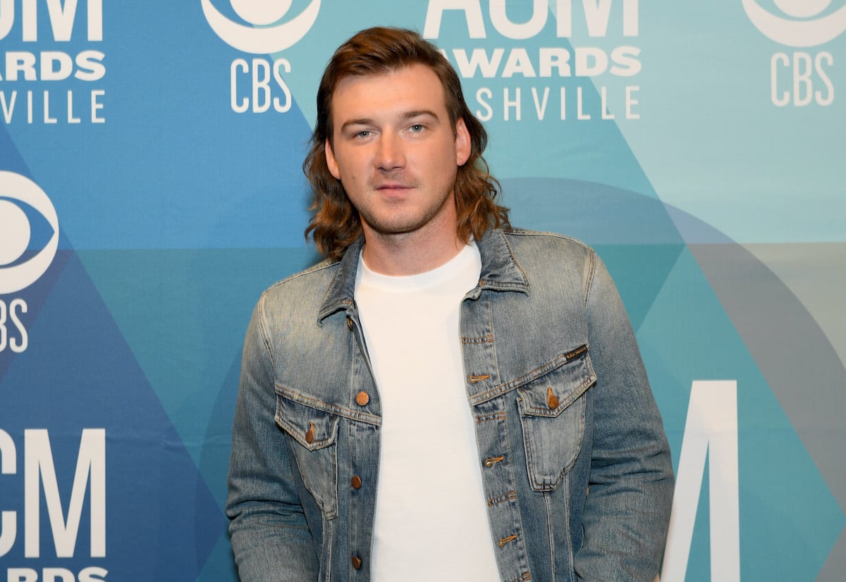 Morgan Wallen, who shares a son with Katie Smith, smiling in front of a blue background