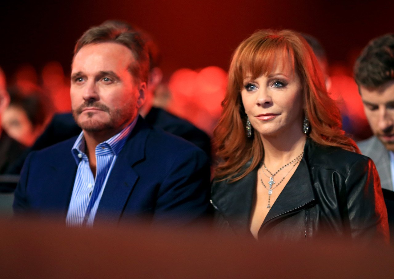 Narvel Blackstock in a dark blue jacket next to Reba McEntire in black